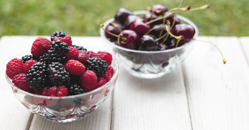 Different berries in a glass bowl on picnic table